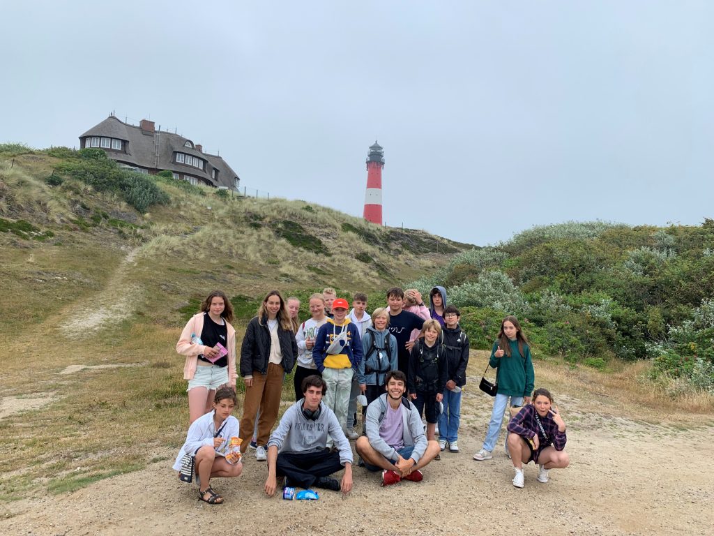 Kids posieren fröhlich vor einem Leuchtturm an der Nordsee. Happy im Englisch Camp der camps for friends!