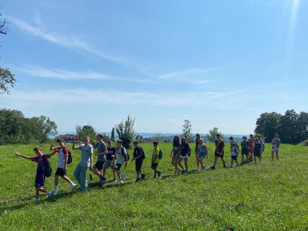 Gruppe von Kids und Teens hat Spaß auf einer Wiese - direkt am Bodensee. Im Englischcamp der camps for friends.